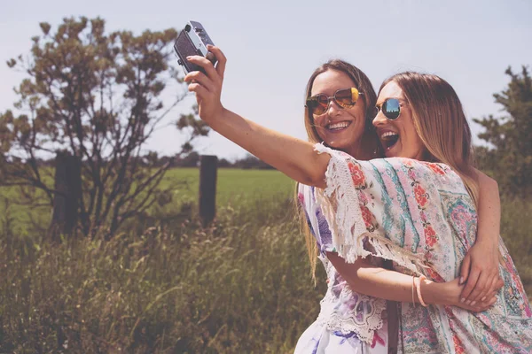 Twin sisters making a selfie with retro camera — Stock Photo, Image