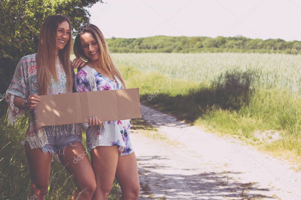 two girl friends waiting with a paper plate to hitchhiking