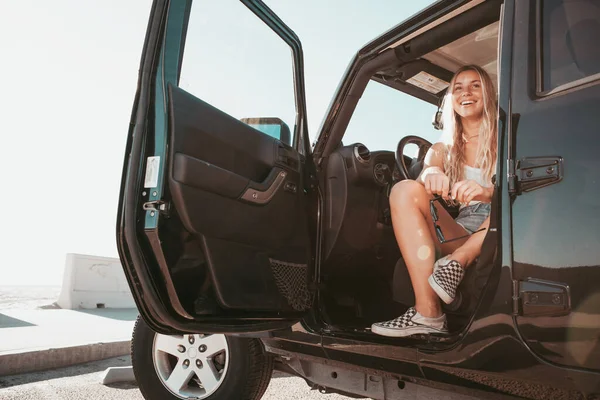 サーファーの女の子がビーチで車に座っている。カリフォルニアのライフスタイル — ストック写真