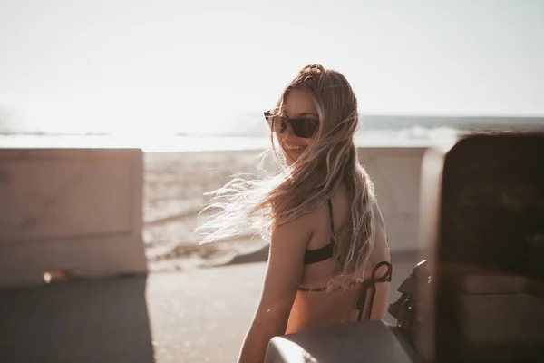 Surfermädchen, das am Strand neben einem Auto steht. kalifornischer Lebensstil — Stockfoto