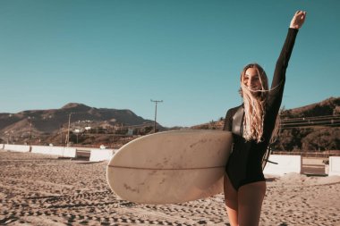 Malibu sahilinde sörf tahtası olan genç bir kadın. California yaşam tarzı