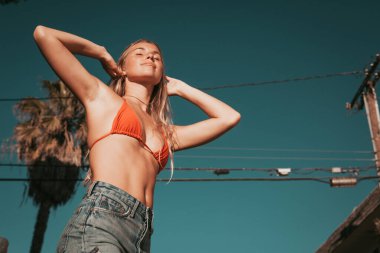 Bikinili ve şortlu genç bir kadın. California yaşam tarzı