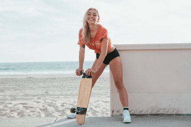 Malibu sahilinde kaykayla duran kaykaycı kız