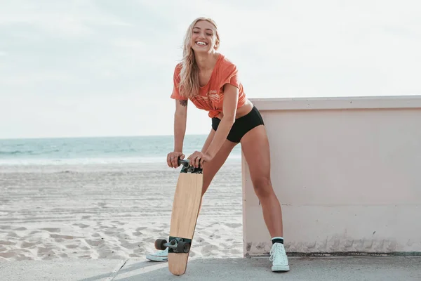 Дівчина ковзаняр стоїть зі скейтбордом на пляжі Малібу — стокове фото