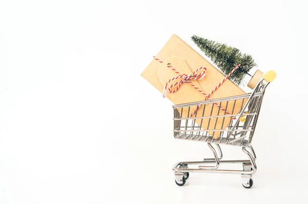 Carrello in metallo per lo shopping con una grande scatola regalo, albero di Natale artificiale . — Foto Stock