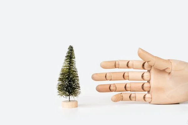 Tahta bir stantta Noel yapay ağacı ve bir elin maketi.