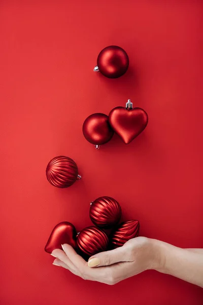 Female hand juggling Christmas round balls and heart shape