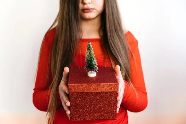 Uzun saçlı bir genç kız elinde büyük kırmızı bir hediye kutusu tutuyor. — Stok fotoğraf