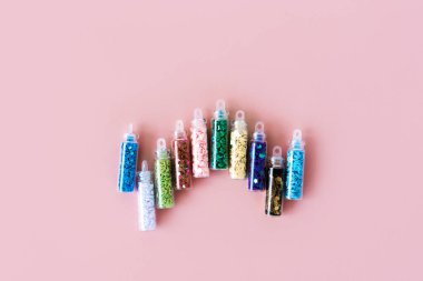 Yumuşak pastel pembe arkaplan kutusu farklı renklerde parıltılar ve pullar dizer