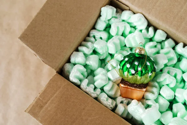 一个装有人造薄荷填料和玻璃圣诞树的纸板箱 — 图库照片