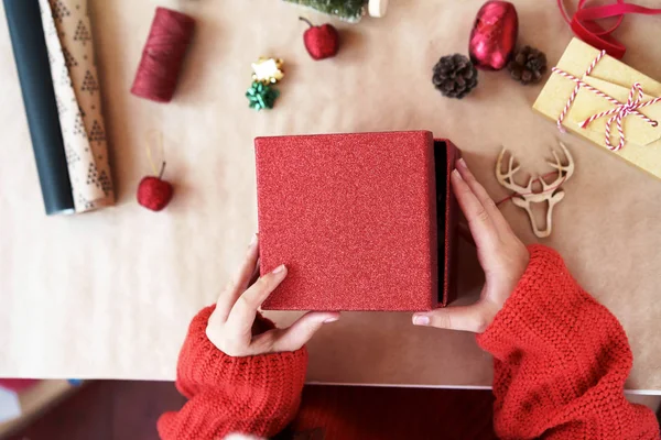 Egy piros pulóveres gyerek kinyitja a piros ajándékdobozt.. — Stock Fotó