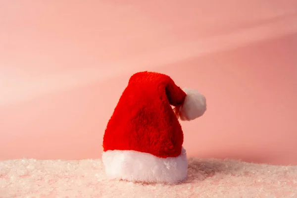 Papai Noel chapéu vermelho com pêlo branco em pé no fundo rosa pastel — Fotografia de Stock