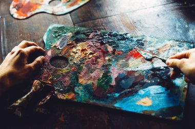 Kadın eli, yağlı boya paletli bir spatulaya müdahale eder.