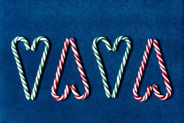 Weihnachtssüße Zuckerstangen in Herzform auf blauem Samtpapier-Hintergrund — Stockfoto