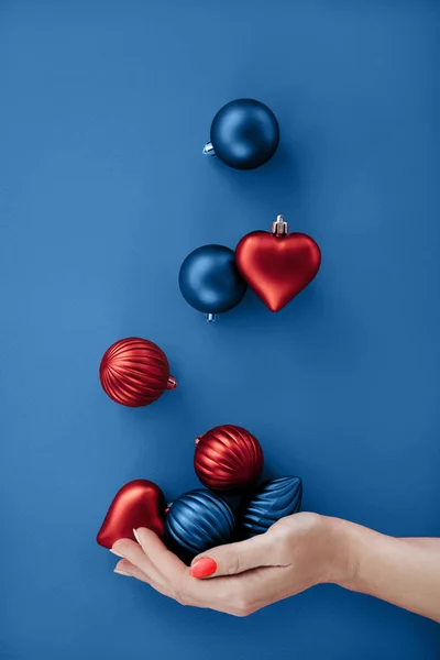 Női kéz zsonglőrködés karácsonyi kerek golyók és szív alakú lapos feküdt — Stock Fotó