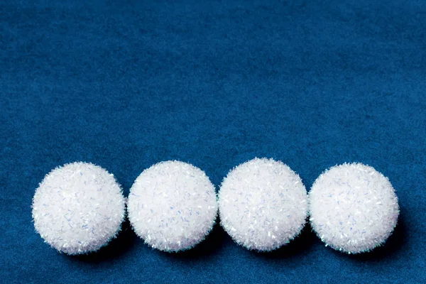 Cuatro estrellas blancas esponjosas de bola de nieve sobre un fondo de papel de terciopelo azul — Foto de Stock