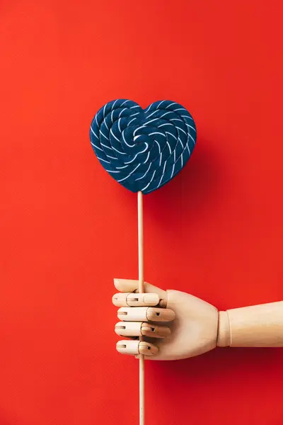 Mano de madera en forma de corazón con una gran piruleta rayada azul y blanca — Foto de Stock