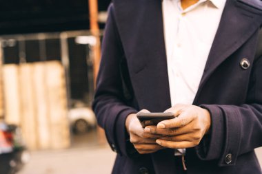 Bir adam elinde telefonla şehirde duruyor. Navigasyon arıyor.