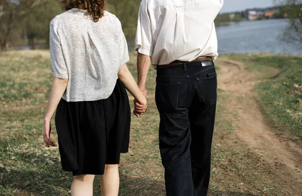 Liebendes Paar älterer Mann und ein junges Mädchen gehen Hand in Hand auf der Natur — Stockfoto