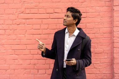 Bir adam elinde telefonla şehirde duruyor. Navigasyon arıyor.