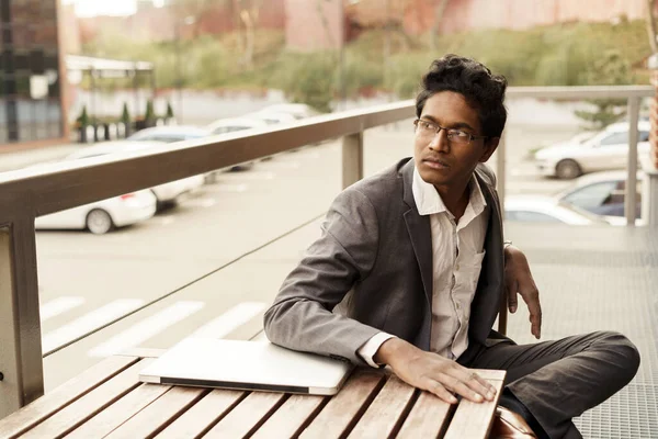 Young handsome Indian man in a white shirt and a business suit is sitting