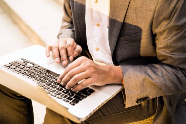 Young mixed race man is sitting with a laptop and typing