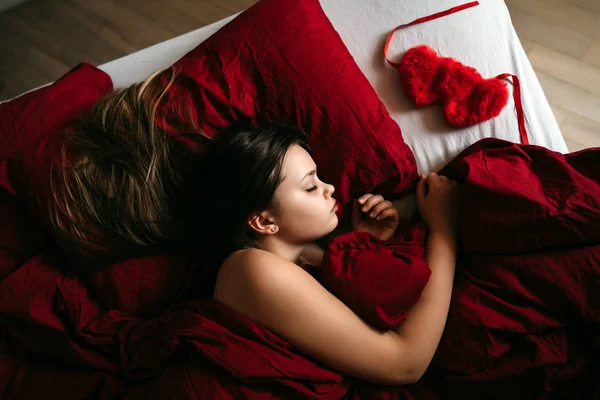 Menina loira com cabelos longos dormindo em um travesseiro de cama vermelho — Fotografia de Stock