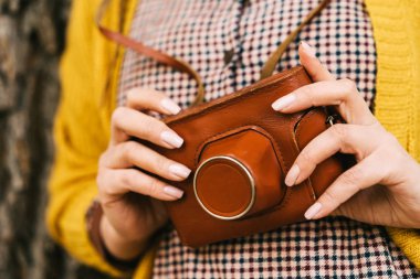 Woman hands with retro photo camera. Fashionable autumn clothes