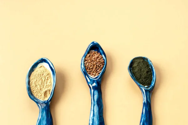 Three blue ceramic clay handmade spoons with flax seeds, chlorella powder, maca — Stock Photo, Image