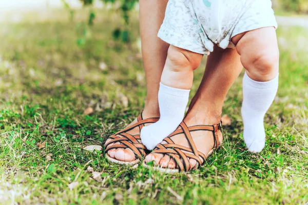 緑の芝生の上で夏のサンダルで女性と子供の足 ストック写真