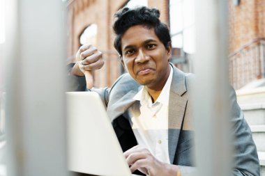 Beyaz gömlekli ve takım elbiseli yakışıklı Hintli genç oturuyor. 