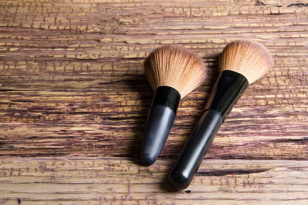 Escovas para maquiagem espalhadas caoticamente sobre fundo de madeira — Fotografia de Stock