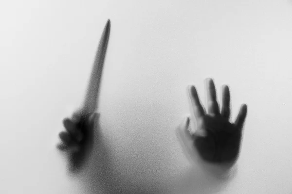 Mãos de sombra com faca do homem atrás de vidro fosco. — Fotografia de Stock