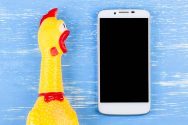 Zeki ile mavi ahşap arka plan üzerinde tavuk shrilling oyuncak sarı