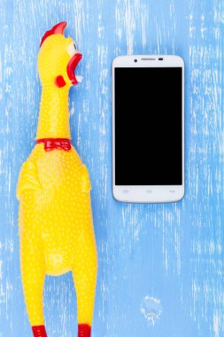 Zeki ile mavi ahşap arka plan üzerinde tavuk shrilling oyuncak sarı