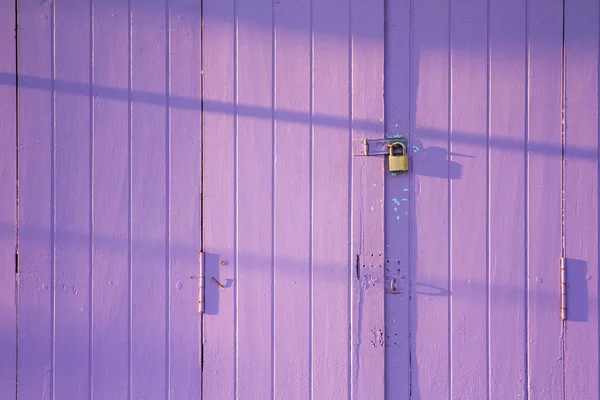 Wooden purple door with lock in the morning.