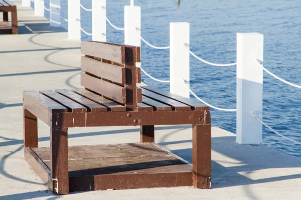 Wooden seat on white cement bridge fishing pier extending into t — Stock Photo, Image