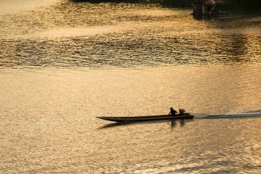 Nehirdeki adam tekne tekne yolculuğu sa gün batımında silüeti