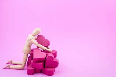 Ahşap kukla ve kağıt yığını pembe bac üzerinde kırmızı kalp şekli kutu