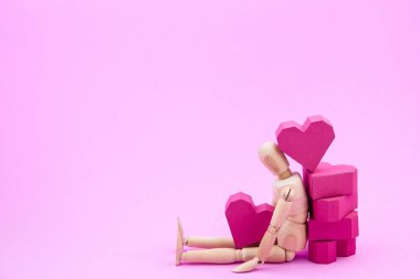 Ahşap kukla ve kağıt yığını pembe bac üzerinde kırmızı kalp şekli kutu