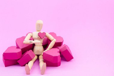 Ahşap kukla ve kağıt yığını pembe bac üzerinde kırmızı kalp şekli kutu