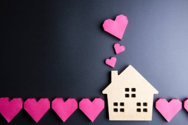 Ahşap ev oyuncak ve kağıt kutu kırmızı kalp şekli üzerinde siyah backgrou