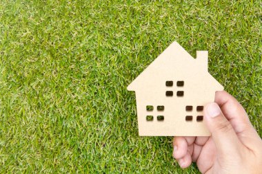 Adamın elini tutmak ahşap ev oyuncak c ile yere yeşil çimenlerin üzerinde