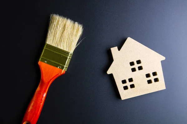 Wooden house toy and construction tools on black background with