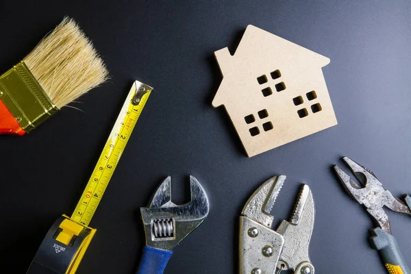 Juguete de casa de madera y herramientas de construcción sobre fondo negro con — Foto de Stock