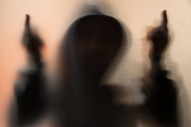 Gölge bulanıklık korku adamın kukuleta ile ceketli. Orta parmak symb