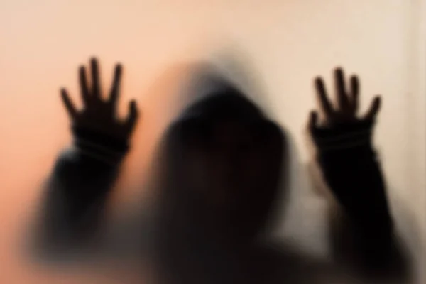 Sombra desenfoque del hombre de horror en la chaqueta con hood.Hands en el vidrio — Foto de Stock