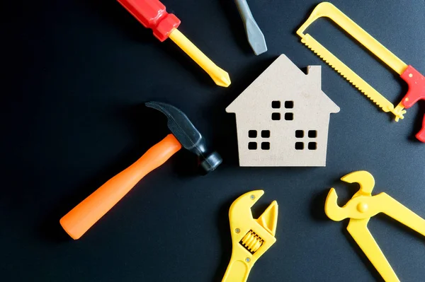 Juguete de casa de madera y juguete de herramientas de construcción sobre fondo negro — Foto de Stock