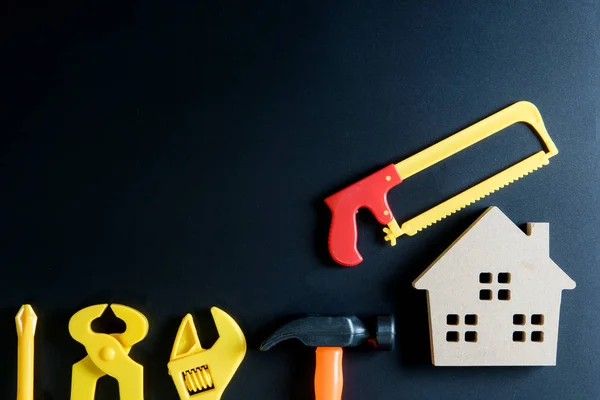 Juguete de casa de madera y juguete de herramientas de construcción sobre fondo negro — Foto de Stock