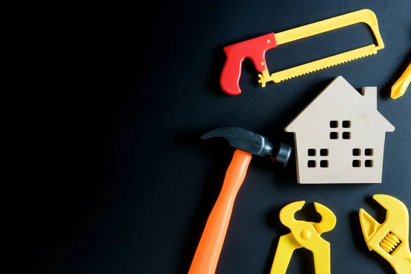 Juguete de casa de madera y juguete de herramientas de construcción sobre fondo negro — Foto de Stock